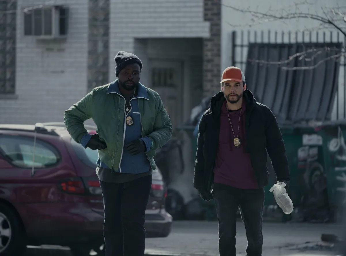 Brian Tyree Henry et Wagner Moura, portant des badges et debout devant une voiture rouge dans «Dope Thief»