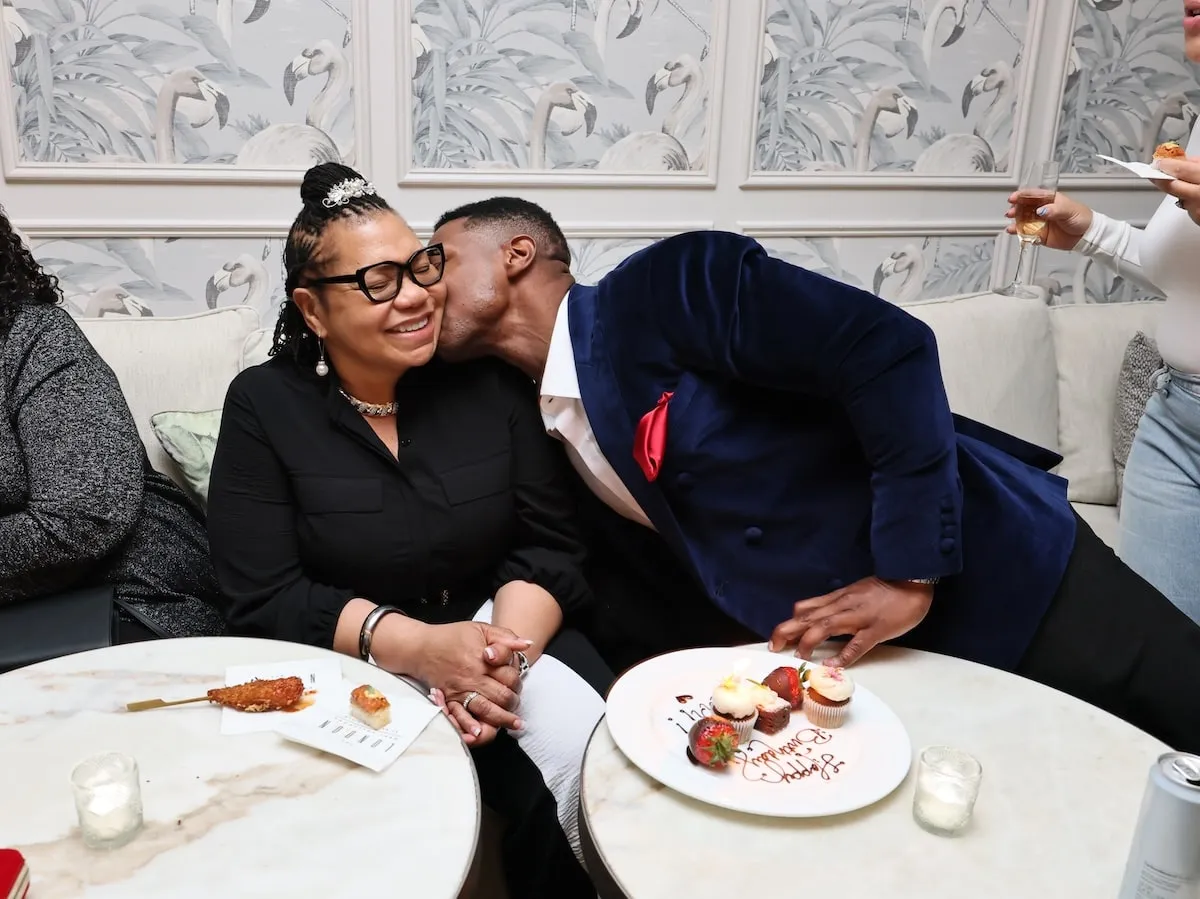 Assis avec sa mère, Jonathan Majors l'embrasse sur la joue lors d'une projection de rêves de magazine